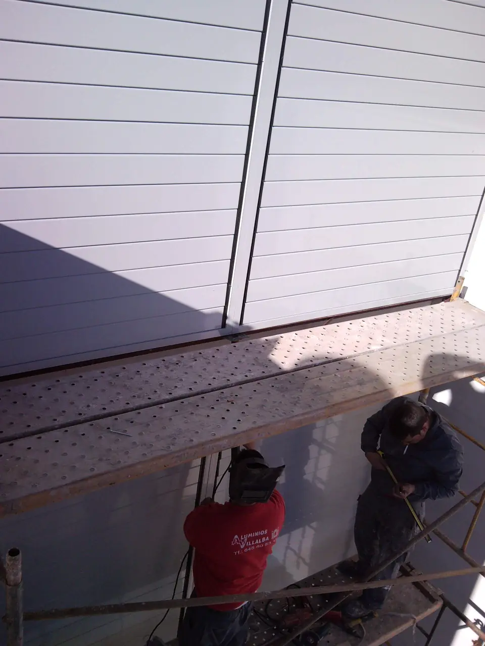 Operarios montando lamas de aluminio en fachada