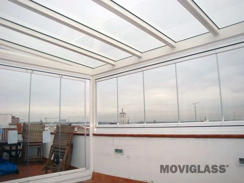 Terraza con techo de cristal y cortinas de cristal abiertas